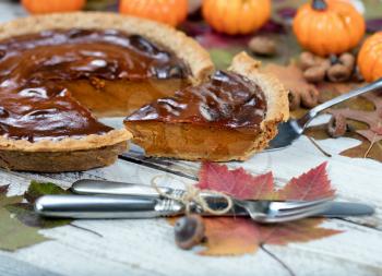 Pumpkin pie with autumn foliage and small pumpkins in background. Thanksgiving holiday concept. 