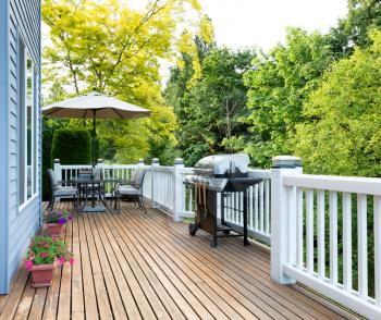 Clean outdoor cedar wooden deck and patio of home with BBQ cooker and bottled beer  