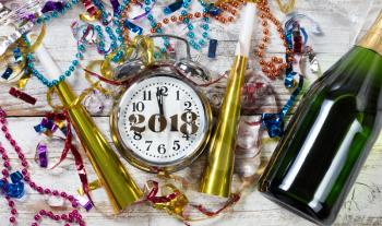 Clock showing Midnight for New Year 2018 surrounded by party objects and Champagne 