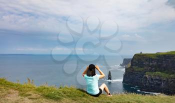 Woman looking into ocean and cliffs