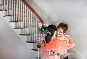 Senior woman receiving gift and flowers from her daughter for Mothers Day