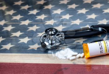 prescription for Hydrocodone or generic opioid with crushed or whole pain killer tablets. Rustic USA flag and medical stethoscope in background for drug addiction concept in America  