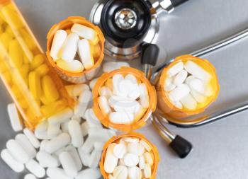 Top view of full prescription bottles with stethoscope and pills on stainless steel background 
