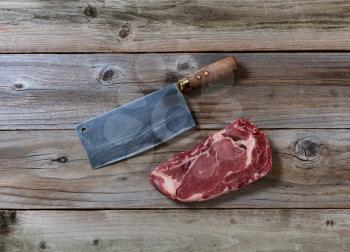 Fresh Raw Prime Beef Steak and Butcher Knife on rustic wooden boards