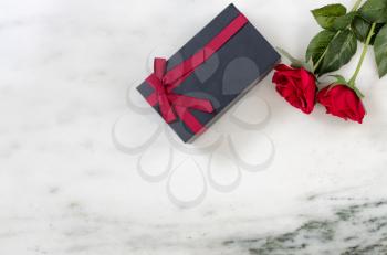 red roses and dark gift box on Marble stone background in flat lay view 