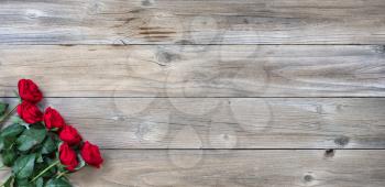 red roses in lower left corner on rustic wood in flat lay view