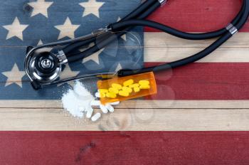 Overhead view of prescription for generic opioid with crushed or whole pain killer tablets. Rustic USA flag and medical stethoscope in background for drug addiction concept in America  