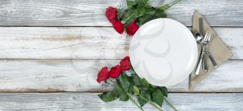 Dinner setting with red roses on rustic white wood in flat lay view for Valentine holiday 