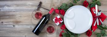 Holiday Dinner setting with red wine and roses on rustic wood in flat lay view