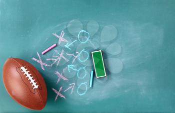 American football with game plan written on cleaned chalkboard 