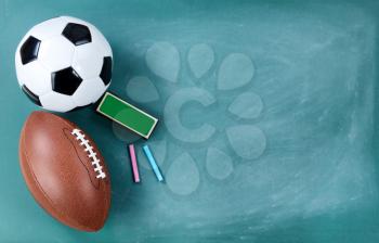 American football and soccer ball on cleaned chalkboard with eraser and chalk