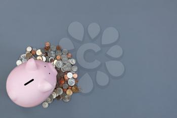 Piggy Bank and coins on gray desktop with copy space