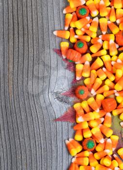 Close up of Halloween candy with autumn leaves on rustic wooden boards