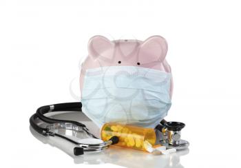 Piggy bank with surgical mask and medical drug supplies isolated on white background with reflection 