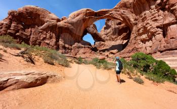 Woman photographing double arch in Utah park 