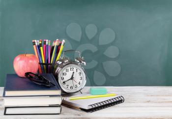 Time for back to school concept including books and stationery supplies with green chalkboard 