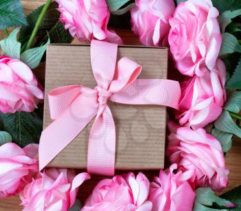 Mothers Day gift box surrounded by pink roses for the holiday season 