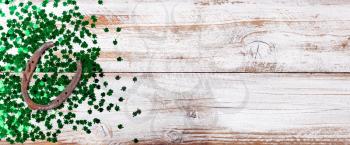 Bright green shamrock and rusty horseshoe for Saint Patrick Day on white rustic wooden background 