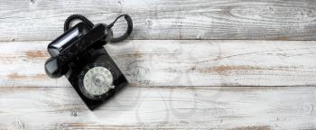 Old fashion rotary dial phone for antique technology concept on white rustic wooden background 