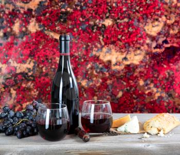 Red wine with cheese and bread on rustic wooden table