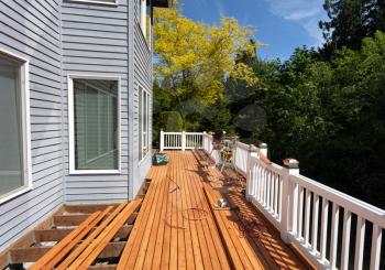 Outdoor wooden deck being remodeled with new red cedar wood floor boards being installed    