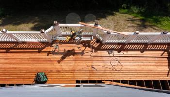 Overhead view of outdoor wooden deck being remodeled with power and hand tools on floor boards
