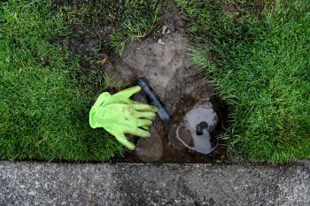 Sprinkler system under maintenance repair with parts and gloves laying on ground  