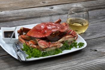 Whole cooked Dungeness crab in dinner table setting with white wine in close up layout 