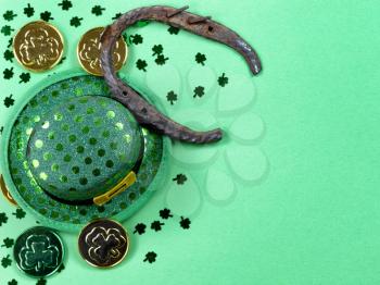 Saint Patricks Day with border of shamrocks, horseshoe and gold coins on green background with copy space