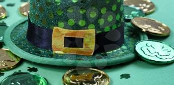 Saint Patricks Day with close up of hat and gold coins on green background 