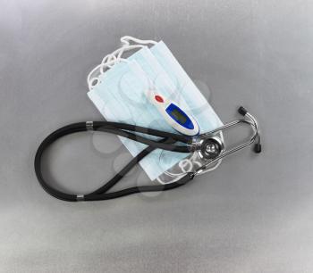 Personal mask, thermometer and stethoscope on stainless steel background for protection against virus or flu concept 