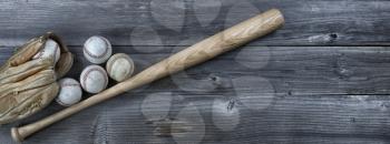 Old used baseballs, bat and weathered glove on vintage wooden background. Baseball sports concept with copy space