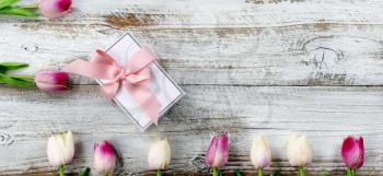 Happy Mothers Day holiday concept with gift box and pink tulips on white rustic wood 