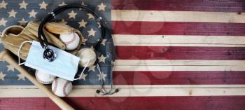 American baseball equipment with surgical protective mask and stethoscope on vintage United States wooden flag background. Coronavirus concept for affect baseball sport season with copy space