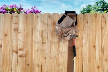 New wooden fence with tool belt and pouch hanging from post 