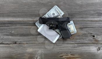 Hand gun and cell phone on top of cash pile for business concept