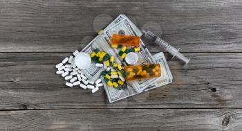 Drug business concept with open pill bottles on top of cash pile 