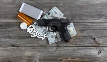 Drug business concept with hand gun and cell phone on top of cash pile 