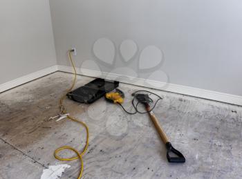 Renovation of home floor with exposed plywood and tools for preparation of hardwood 