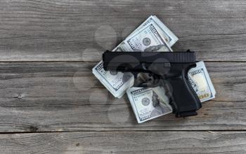 Hand gun on top of cash pile for business concept