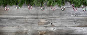 Merry Christmas and Happy New Year with fir branches and candy canes on rustic wooden boards 