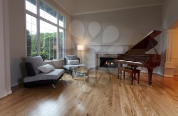 Newly remodeled large living room with glowing fireplace and piano on red oak wood floors 