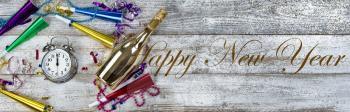 Clock strikes midnight for happy New Year concept with golden champagne and party decorations plus text message