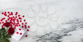 Happy Valentines Day with lovely red rose flowers plus a gift box and hearts on natural marble stone background 