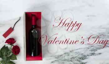 Happy Valentines Day with lovely red rose flowers and red wine bottle in a giftbox on natural marble stone background 