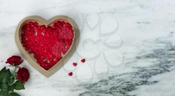 Happy Valentines Day with lovely red rose flowers plus large heart shaped giftbox filled with small hearts on natural marble stone background 