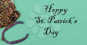 St Patricks day Irish good luck horse shoe and gold coins on a green paper background with copy space plus text message