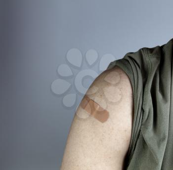 Band aid on male upper arm after coronavirus vaccine shot 