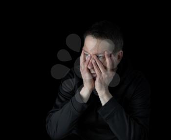 Depressed mature man holding his face with both hands while looking into dark emptiness display stress
