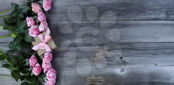 Light pink roses and giftbox on rustic wooden boards for Mothers Day concept in flat lay format  